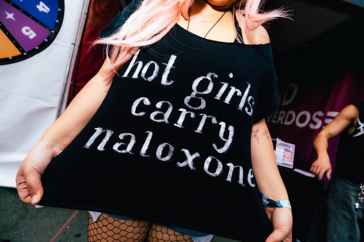 A festival-goer in a shirt that reads hot girls carry naloxone